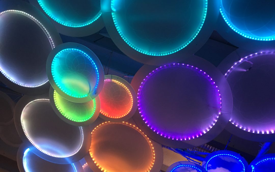 lots of circles illuminated with colourful neon lighting, blues, purples, greens,, oranges and whites are used.