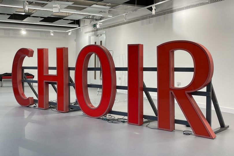 One and a half metre high letters supported by a wooden letters spell out the word CHOIR in red.
