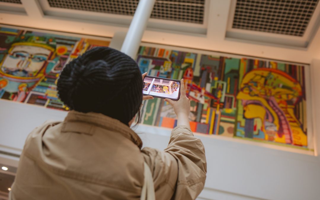 A person holds their smartphone up to a large mural showing an animation on the phone screen.