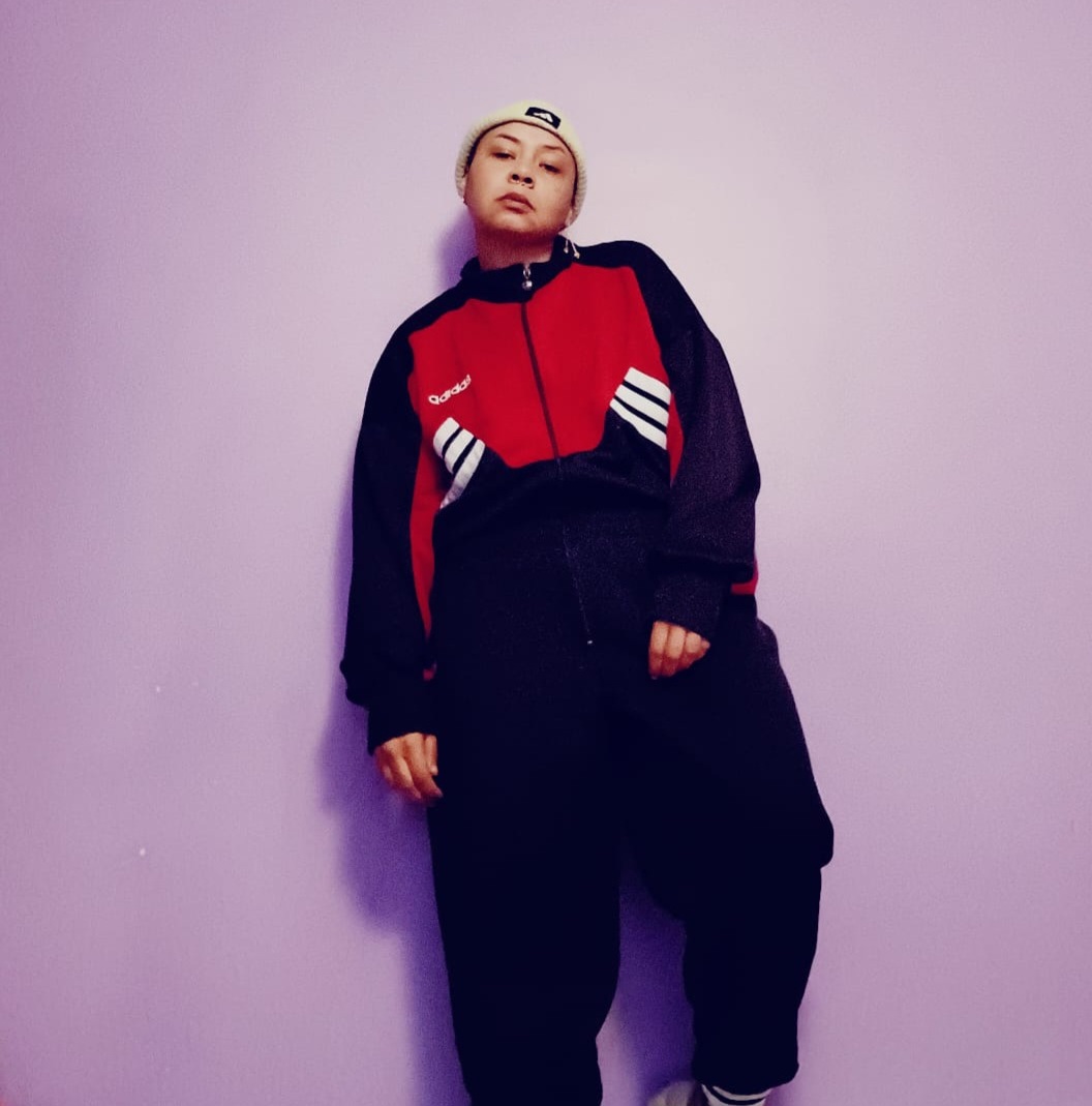 They/them in red and black sportswear on a pink background.